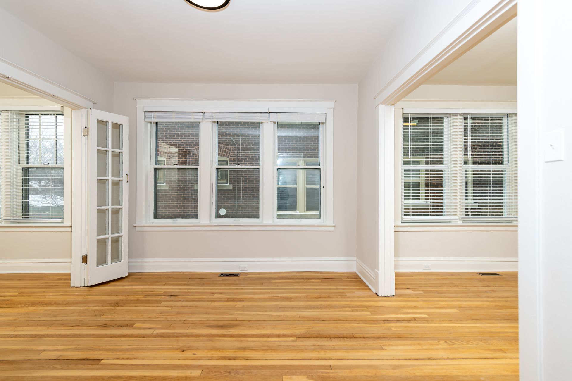 An empty living room with hardwood floors and two windows.