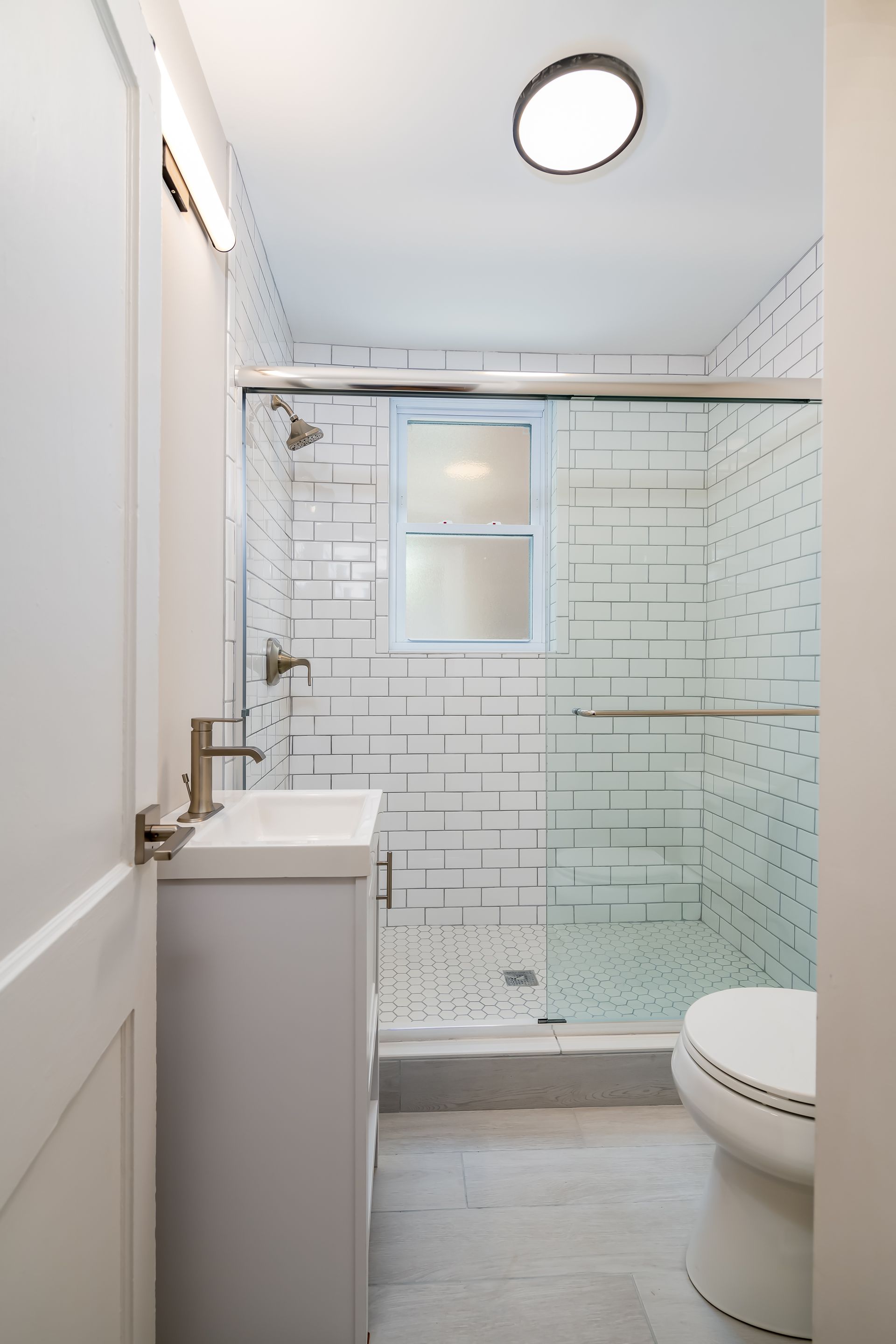 A bathroom with a toilet , sink and shower.
