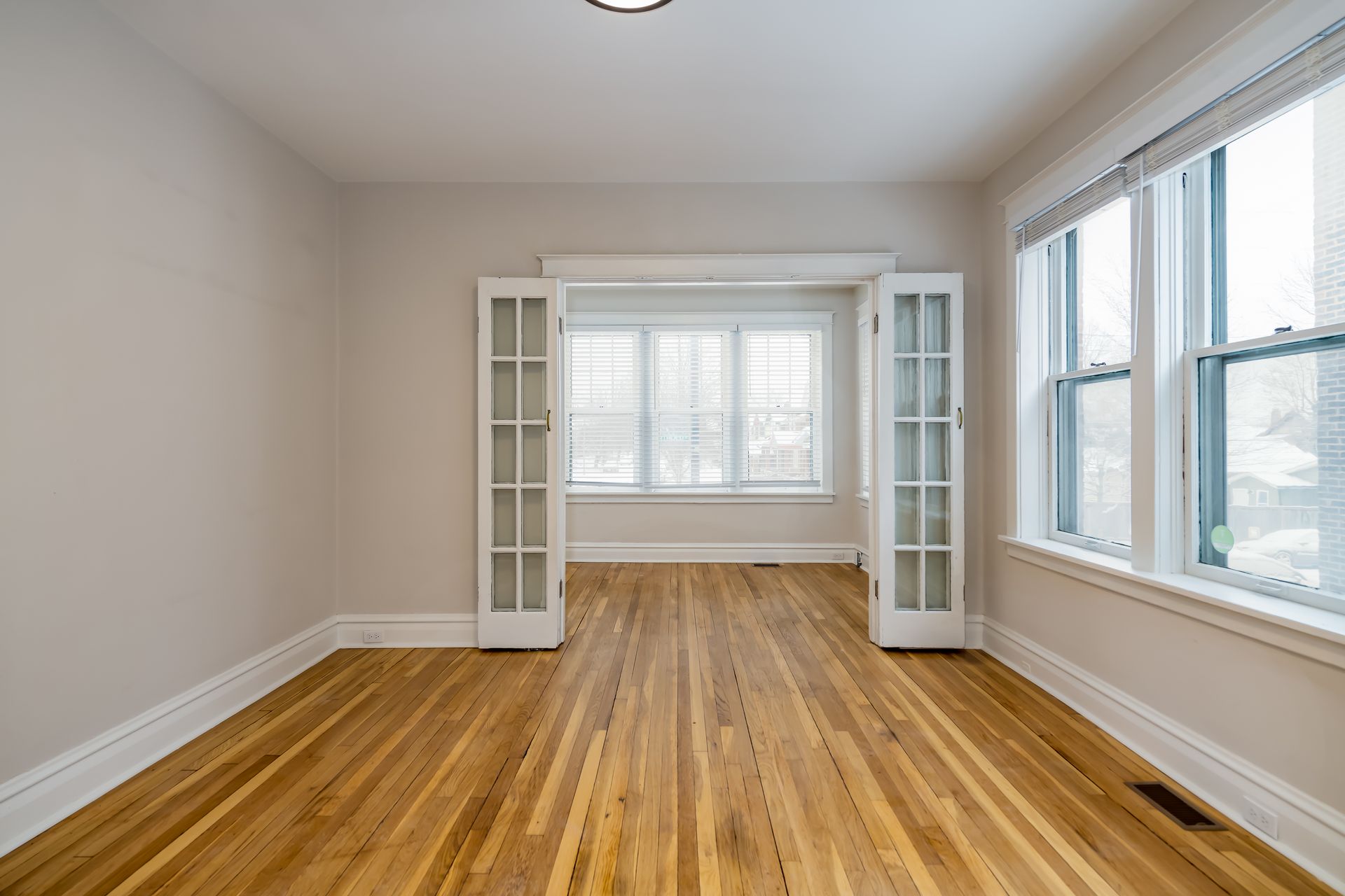 An empty living room with hardwood floors and french doors.