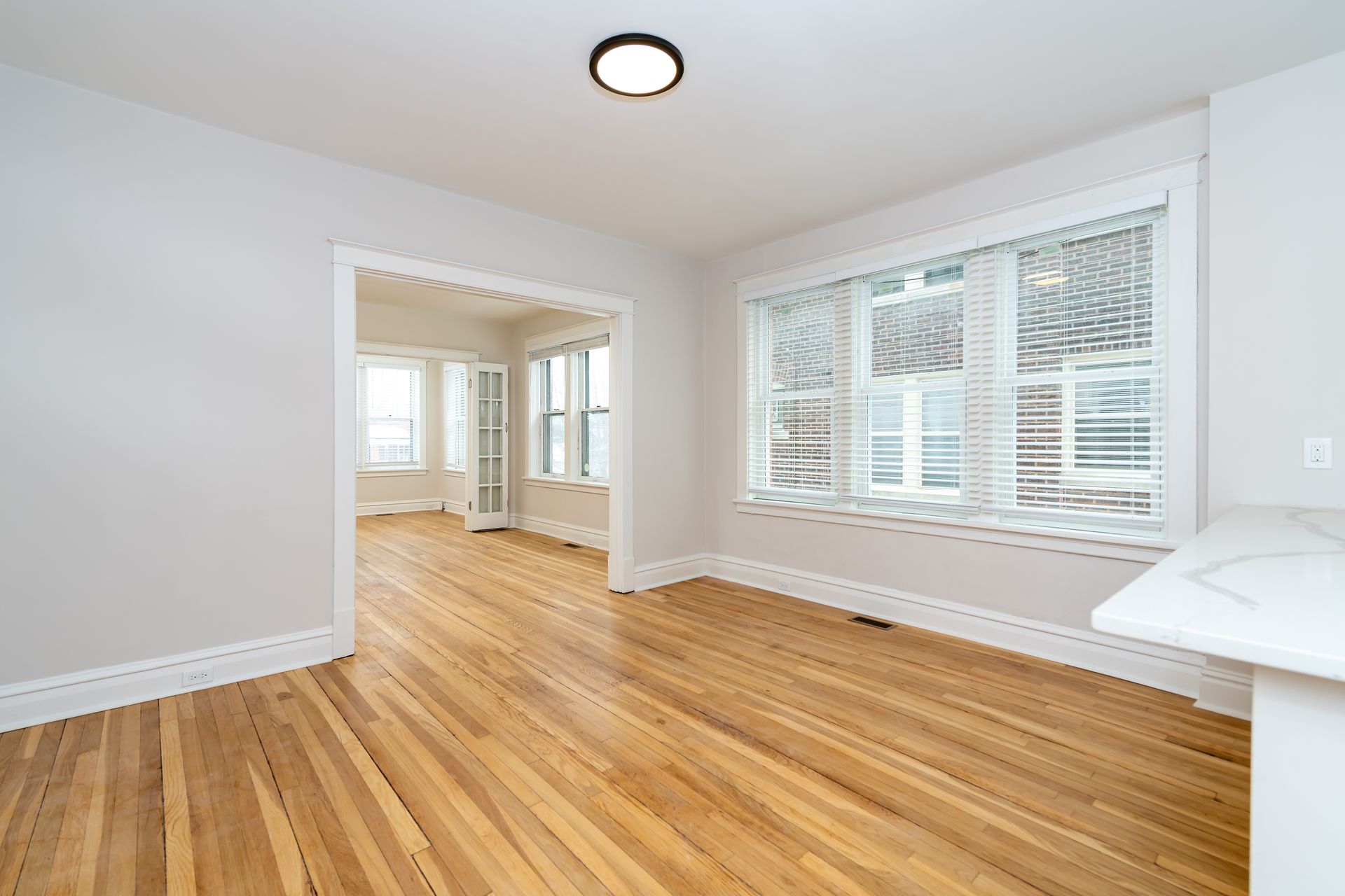An empty living room with hardwood floors and white walls.