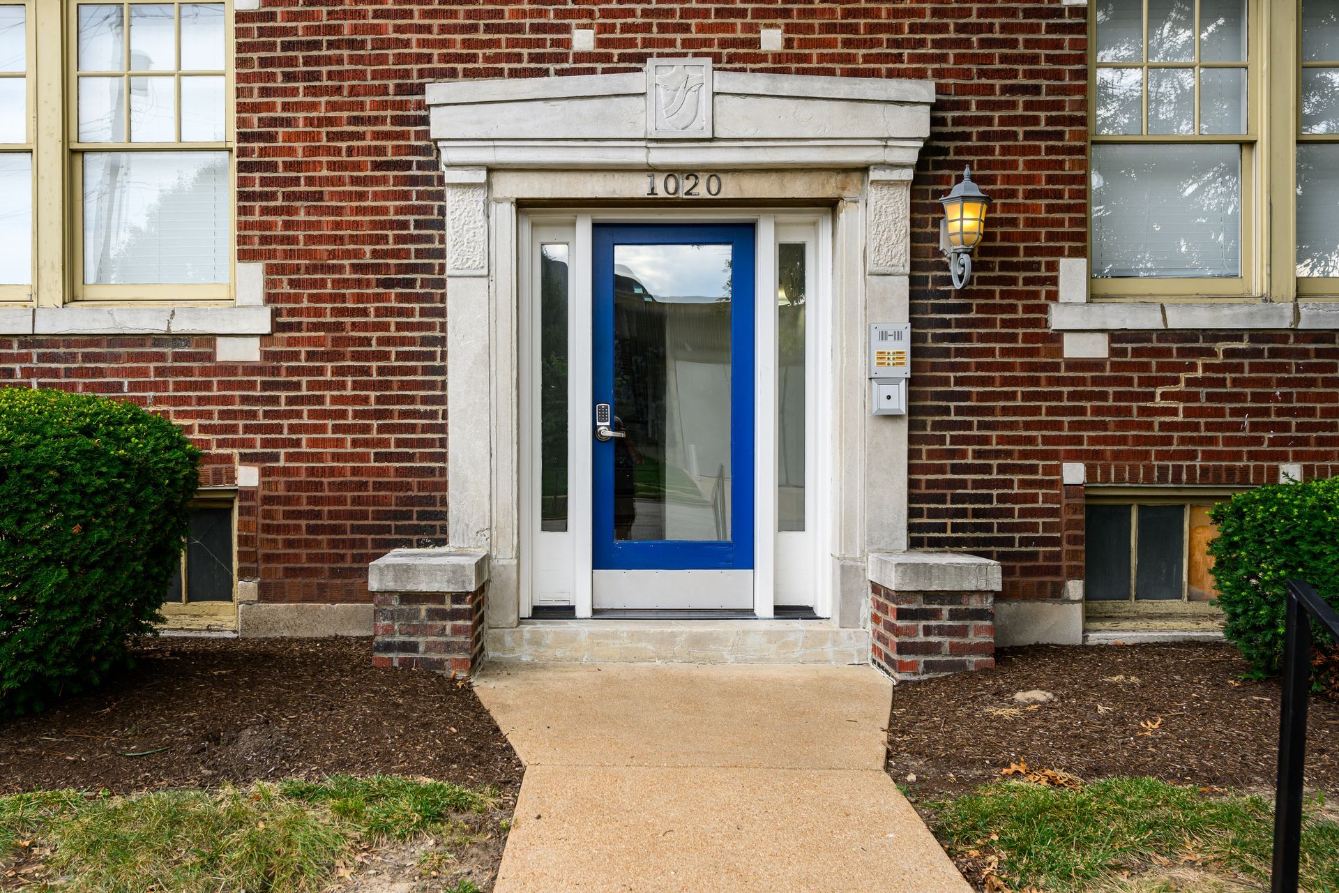 A brick building with a blue door and a walkway leading to it.