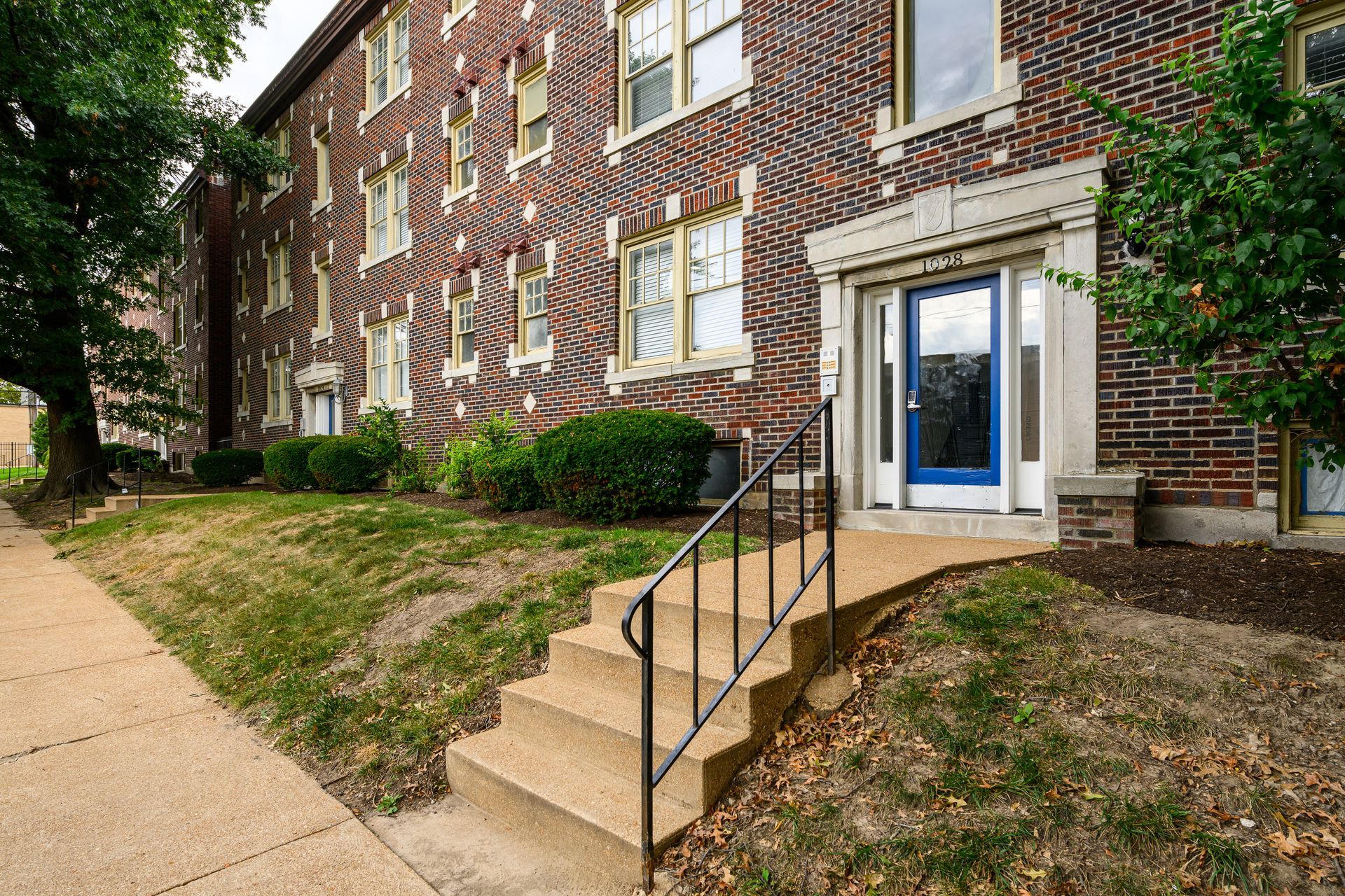 A brick building with a blue door and stairs leading up to it.
