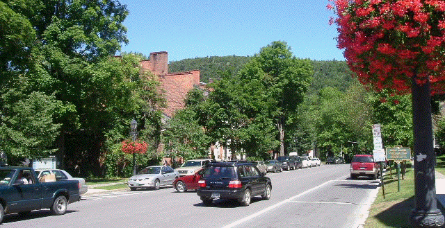 A row of cars are parked on the side of a street.