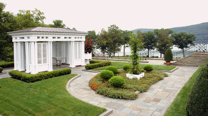 A white gazebo is in the middle of a lush green garden.