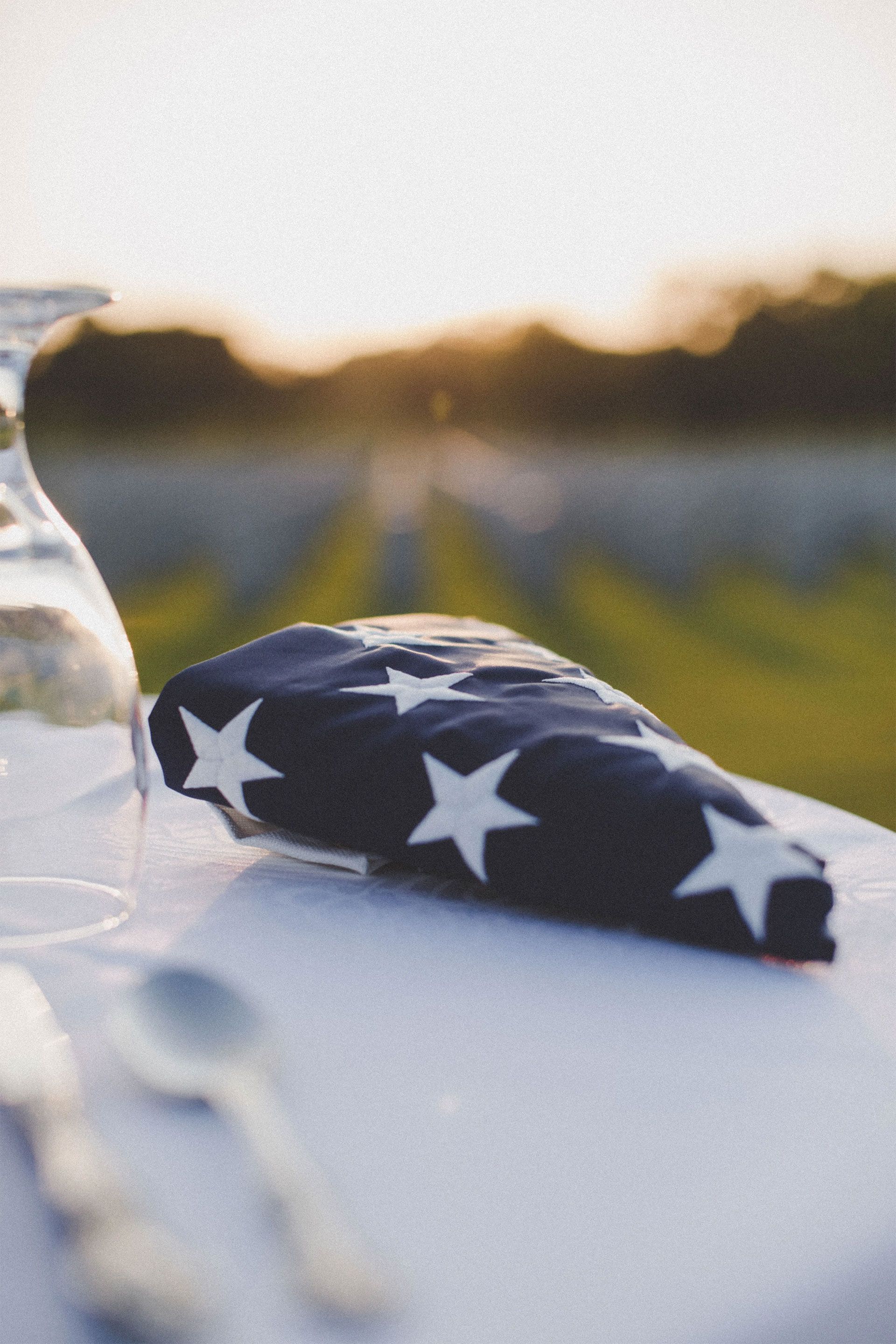 A woman is holding an american flag and a rose at a funeral.