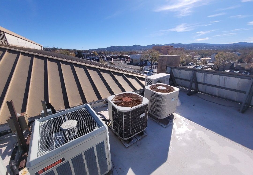 Three rooftop air conditioning units under a sunny blue sky.