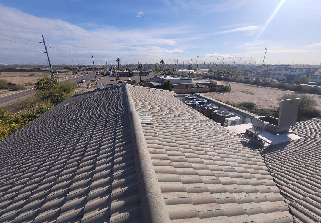 Overhead view of a tile roof with a desert landscape background on a sunny day.