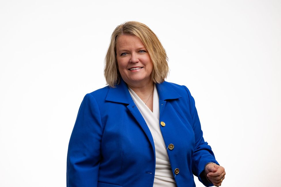 Dr. Celina in blue blazer smiles, posing in front of a white background.