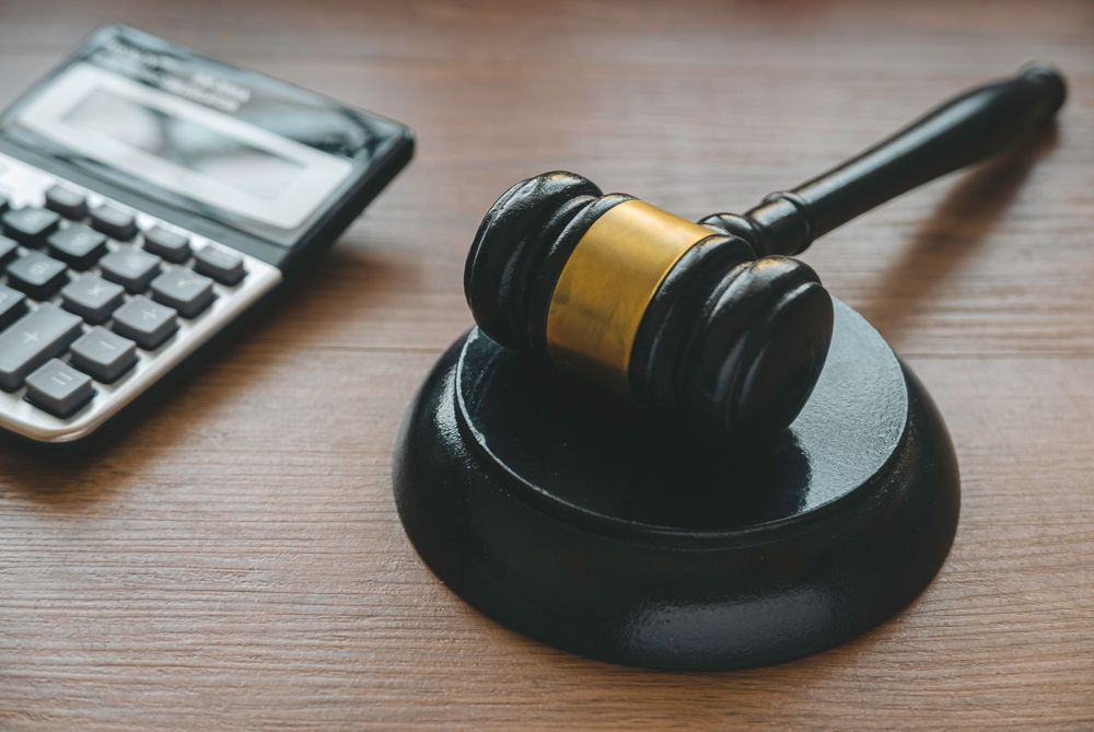 Judge’s gavel beside a calculator on a wooden desk