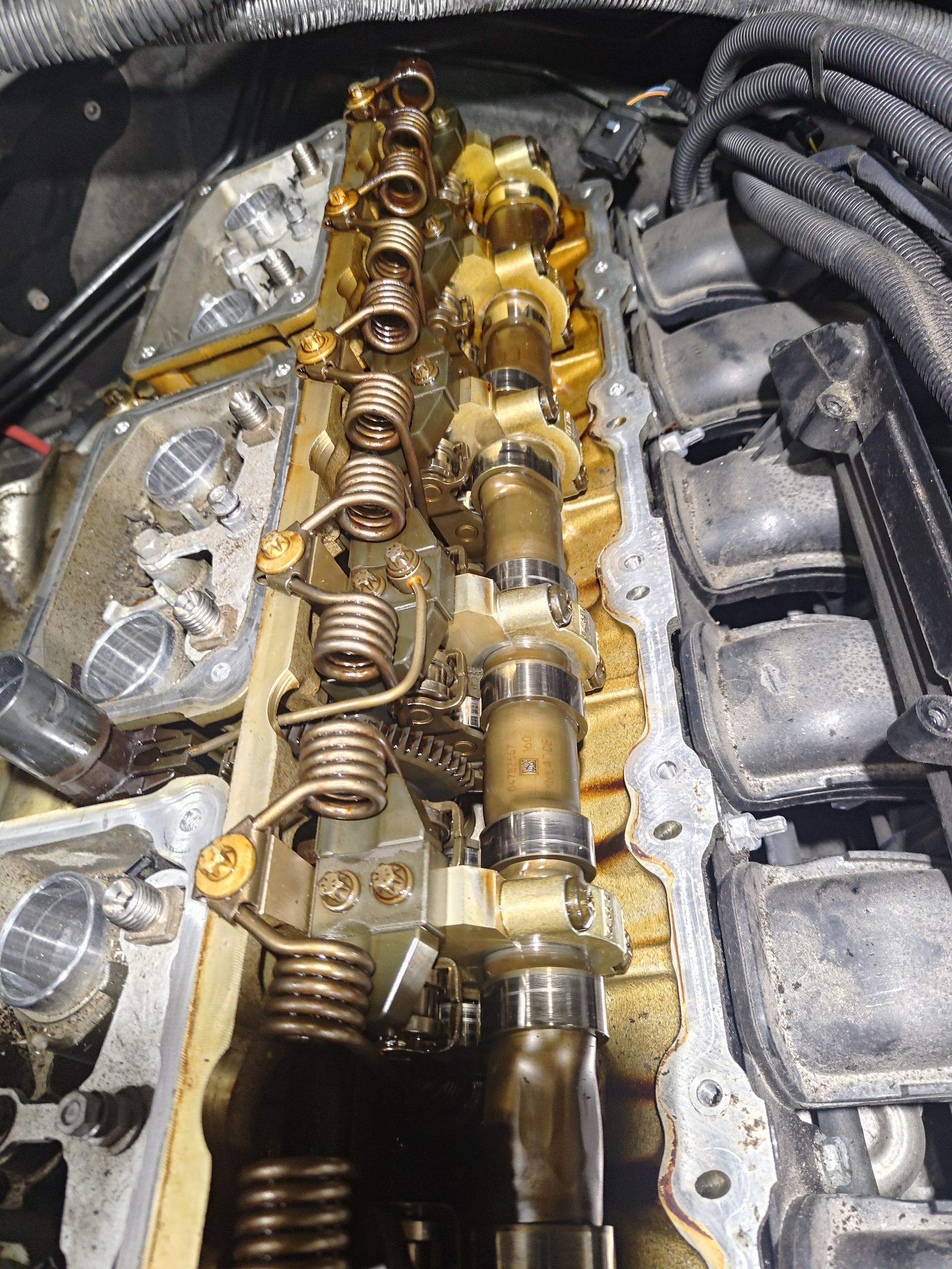 Engine top open, showing camshafts, valve springs, and other internal parts, in gold and silver colors | La Saga Auto