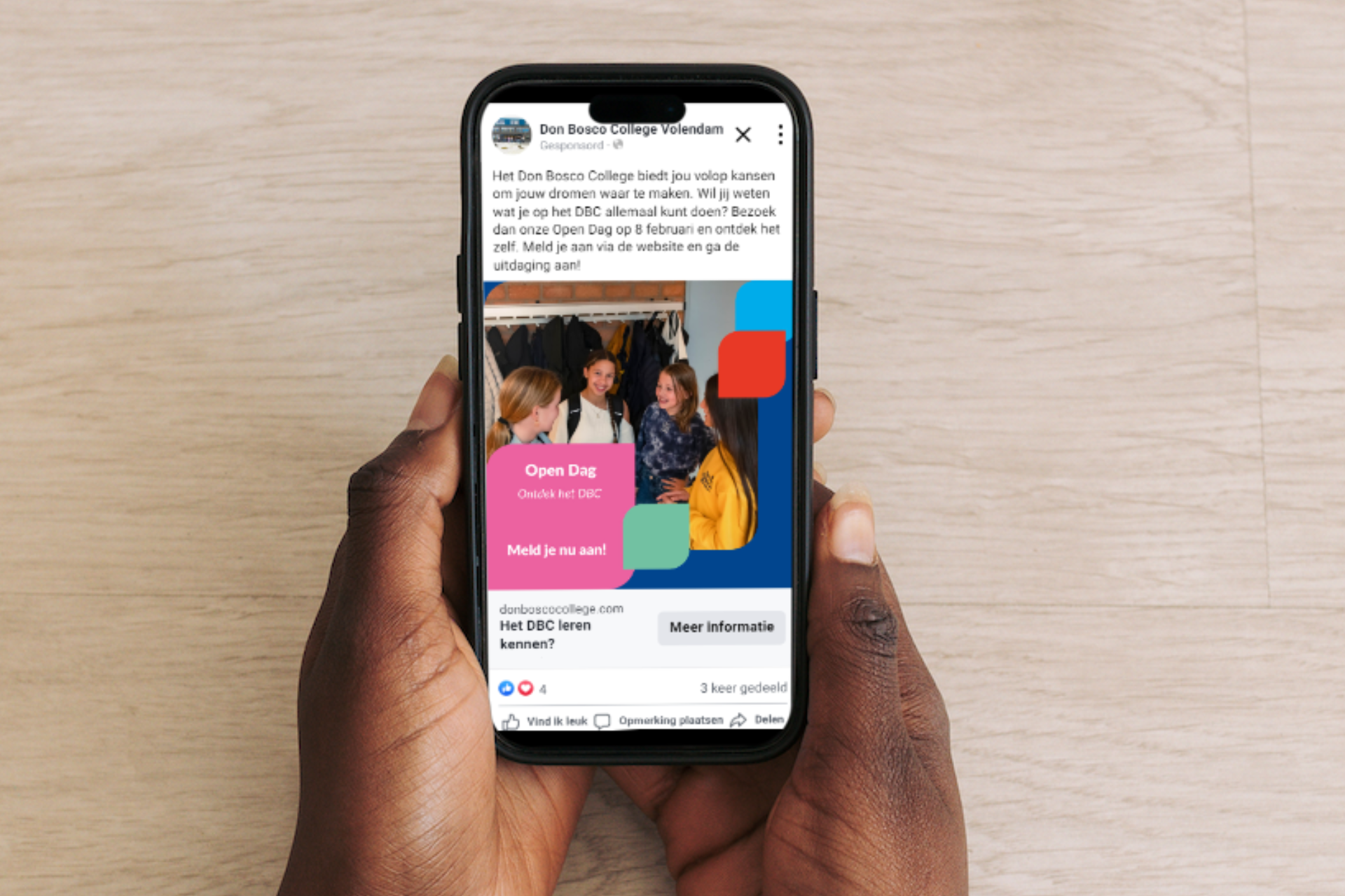 Een persoon houdt een mobiele telefoon vast met een Facebook-advertentie erop.