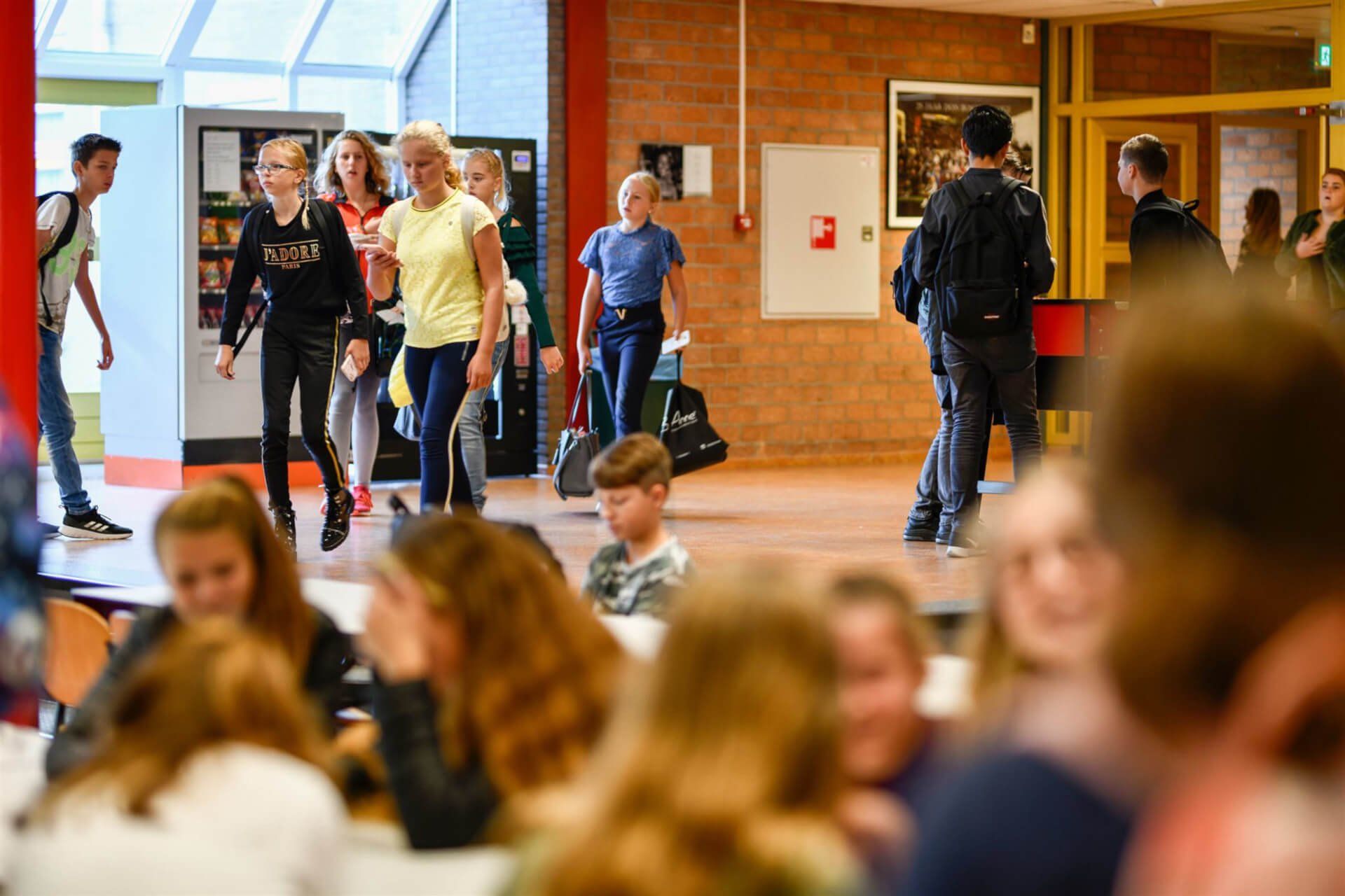 Een groep kinderen loopt door de gang van een school.