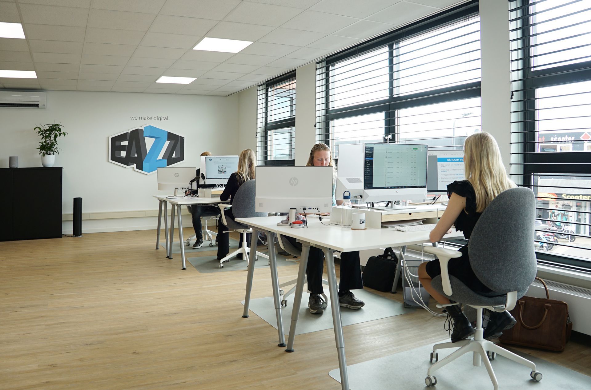 Het team van EAZZI zit aan een bureau in een kantoor.