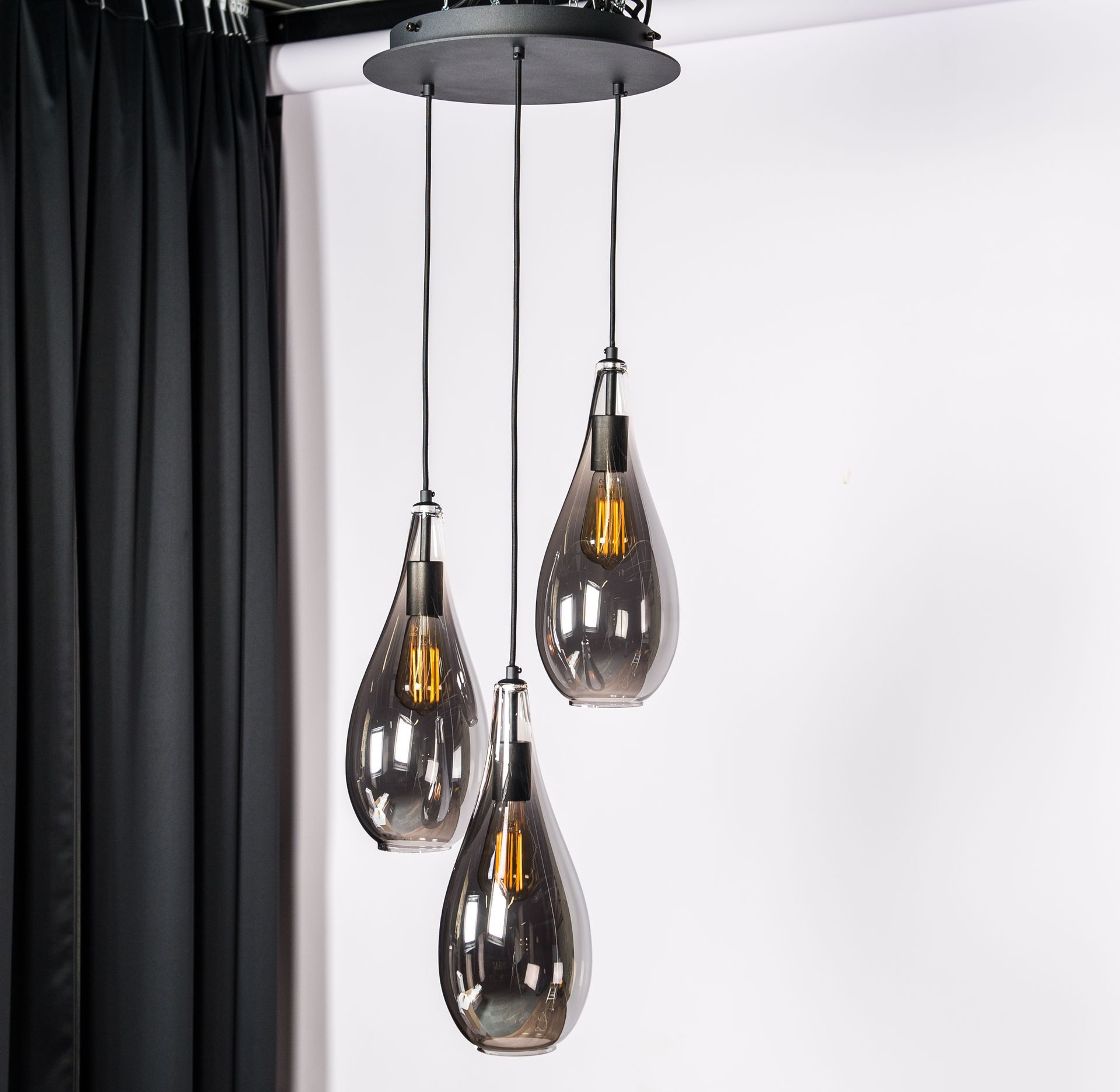 Een hanglamp met drie rookglazen kappen die aan het plafond hangen.