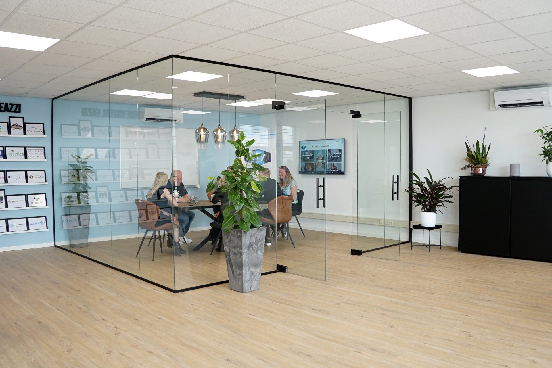 Het team van EAZZI zit rond een glazen tafel in een vergaderruimte.