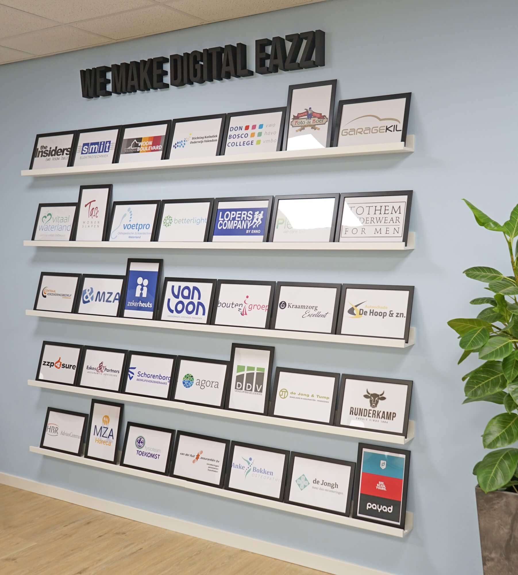 Een muur met planken vol foto's van klantenlogo's. 