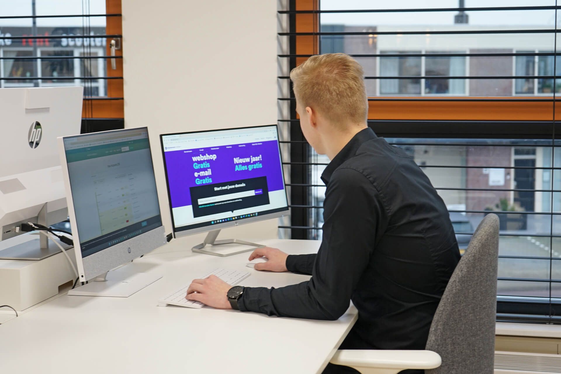Kevin zit aan een bureau voor twee computerschermen.
