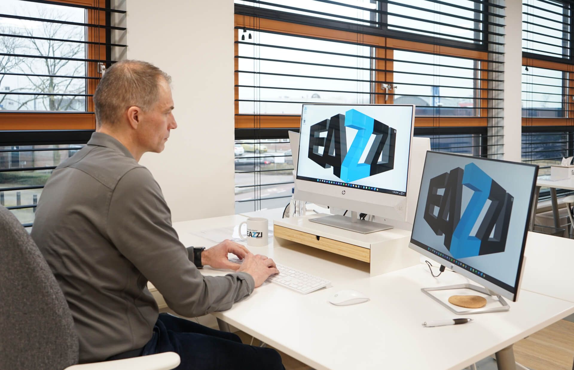Erwin zit aan een bureau voor twee computerschermen.