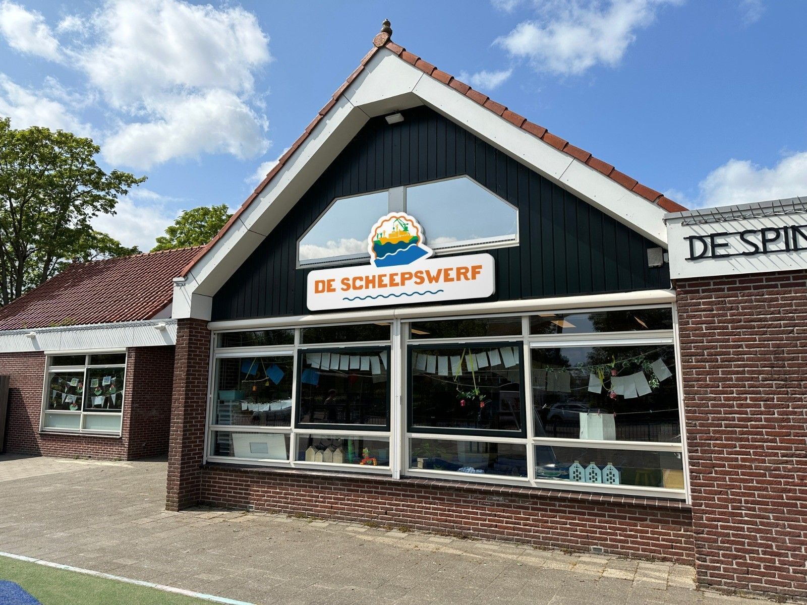 Een schoolgebouw met een bord waarop de scheepswerf staat.