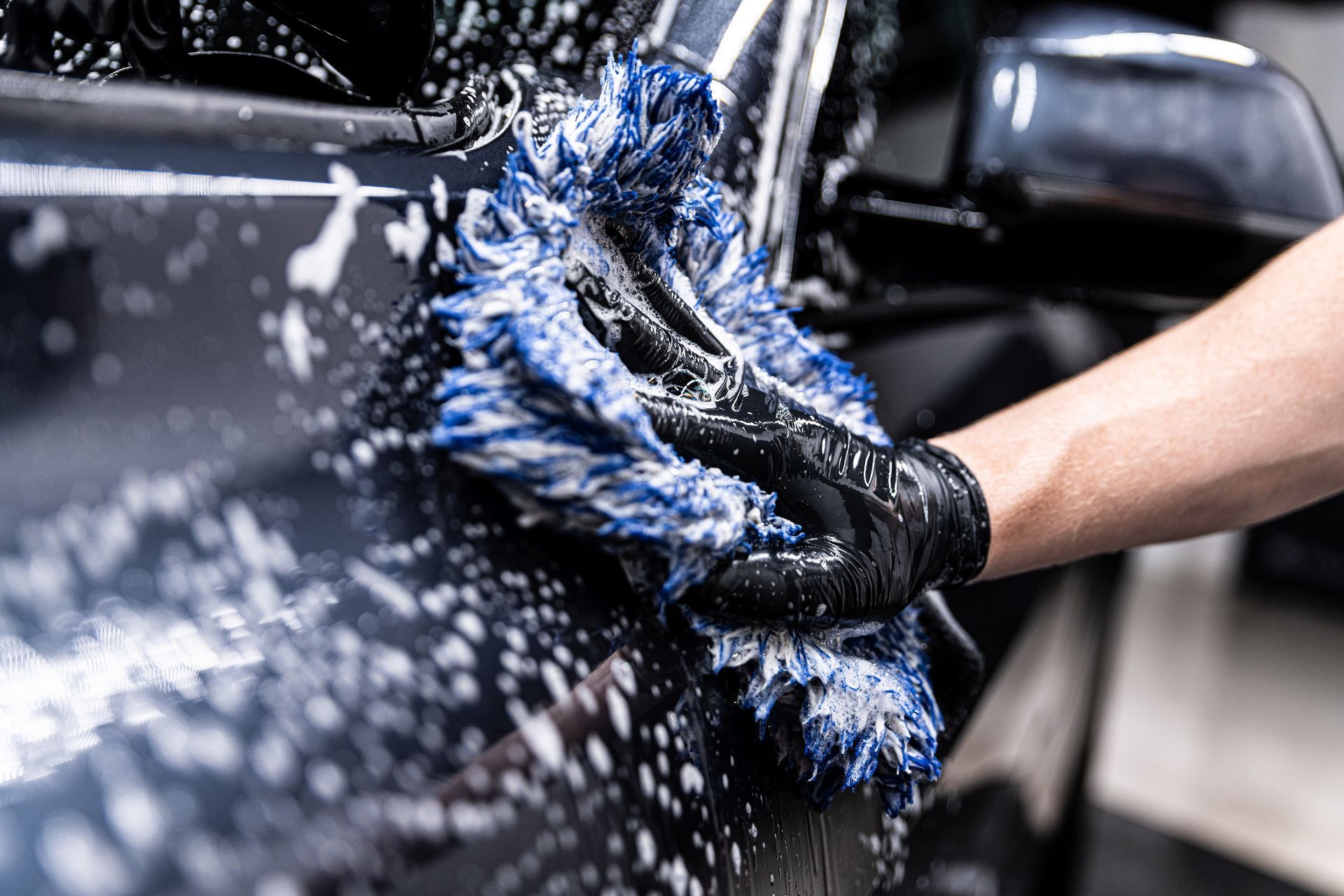 Eine Person wäscht ein Auto mit einem blauen Tuch.