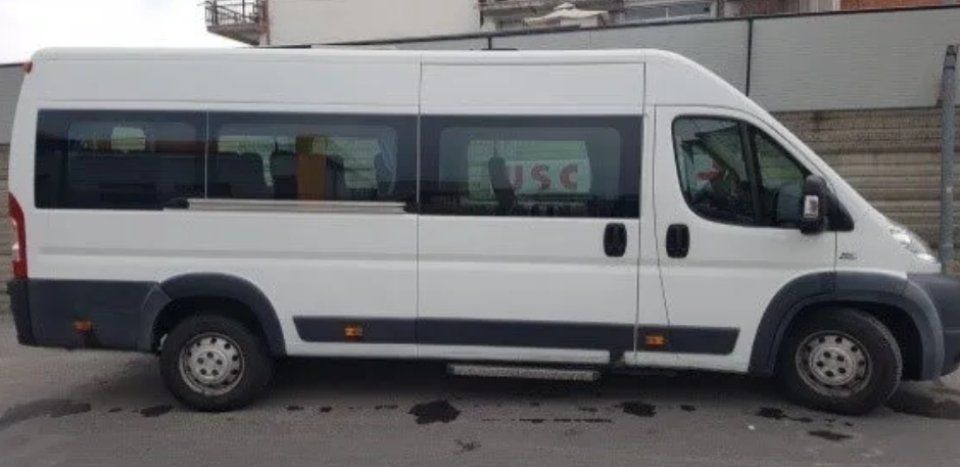 Furgone passeggeri bianco parcheggiato in strada accanto a un muro