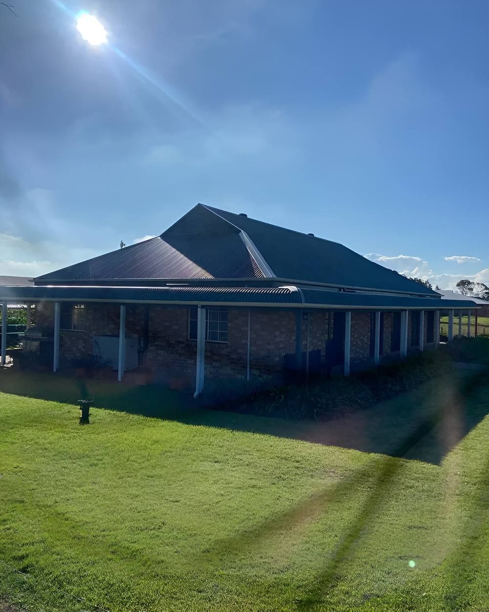 A House With a Covered Porch and a Blue Roof — Lake Valley Roofing in Adamstown, NSW