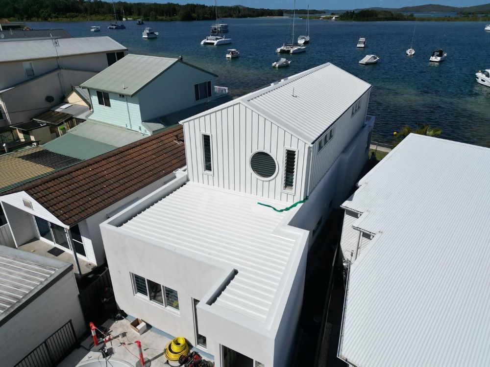 An Aerial View of a White House Next to a Body of Water — Lake Valley Roofing in Kotara, NSW