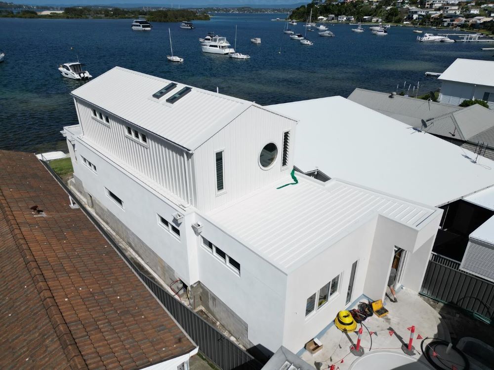 An Aerial View of a White House With Boats in the Background — Lake Valley Roofing in Merewether, NSW