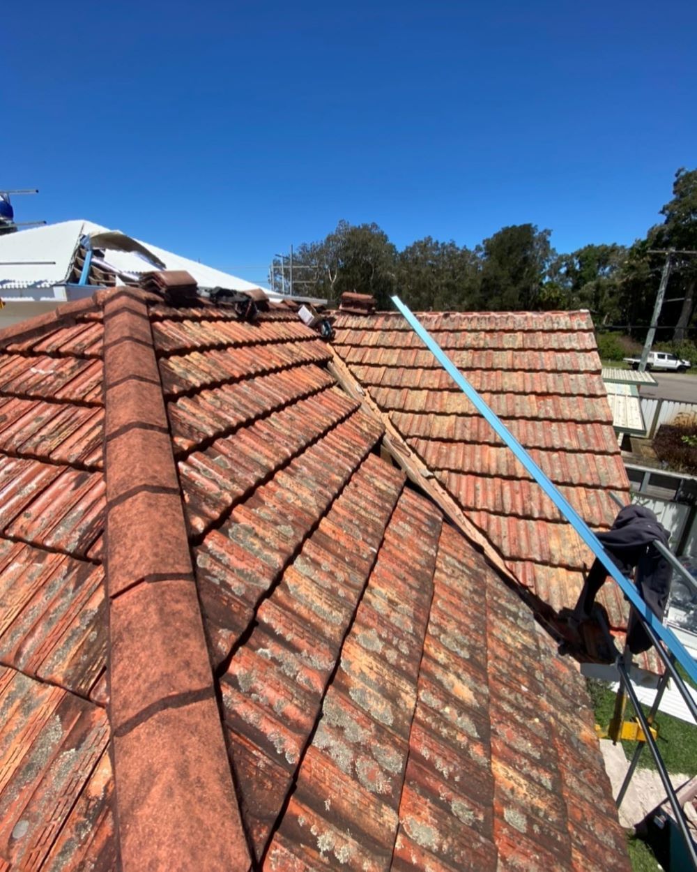 A Man is Working on the Roof of a House — Lake Valley Roofing in Mayfield, NSW