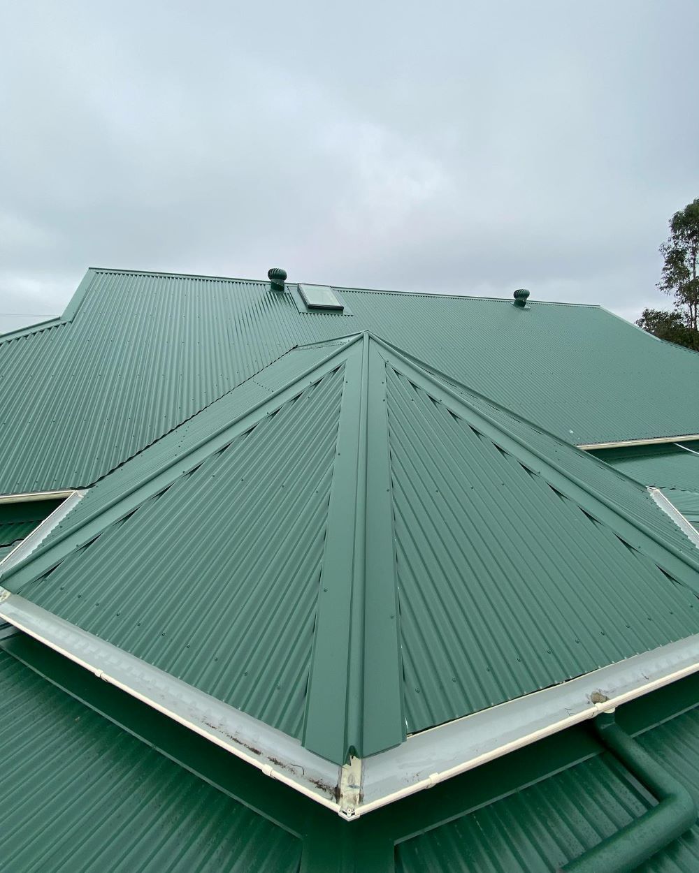 A Green Metal Roof With a White Trim on a House — Lake Valley Roofing in Raymond Terrace, NSW