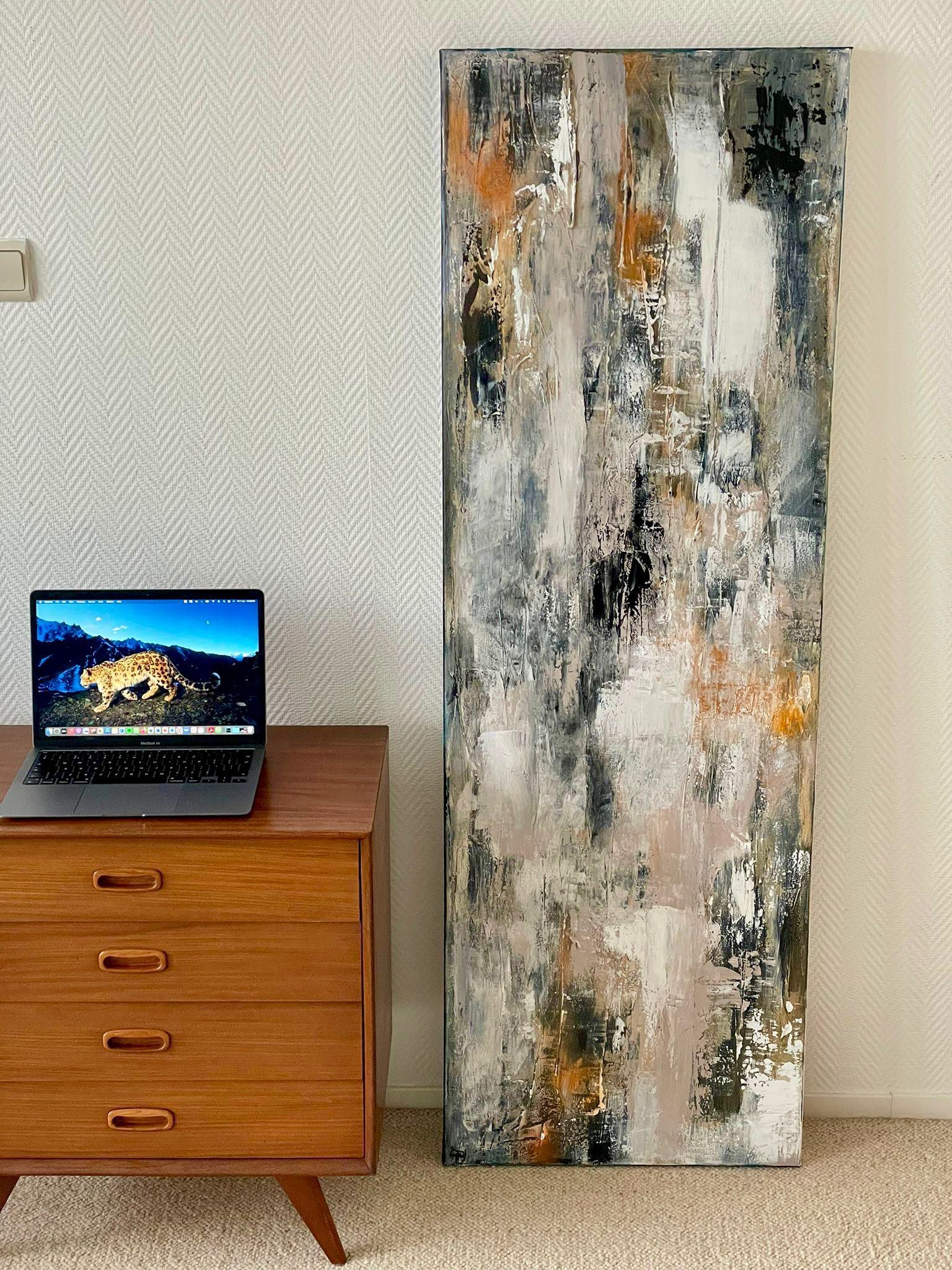 Mid-century modern desk with laptop and abstract art piece with grey, white, and orange tones.