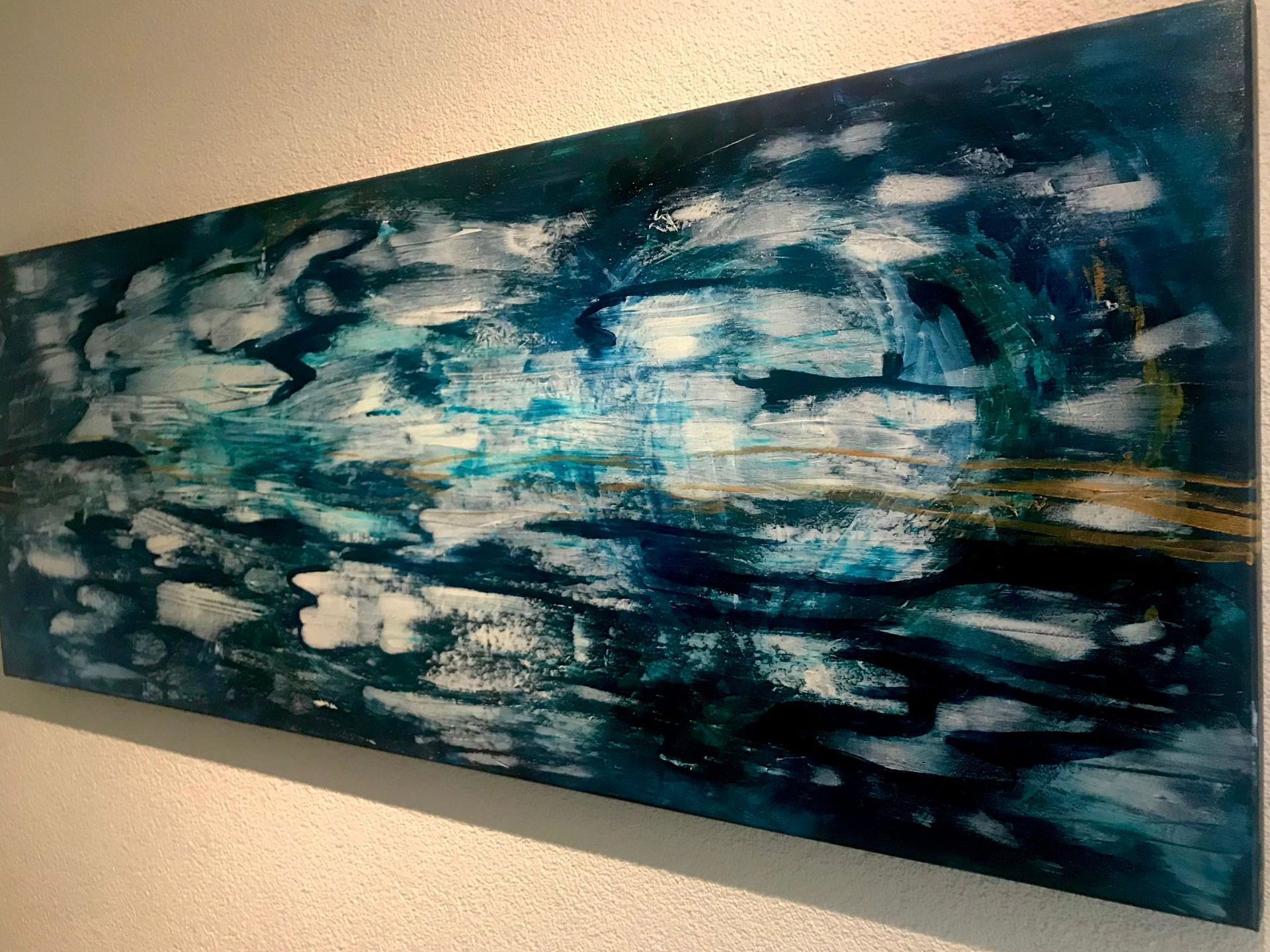 Abstract painting in blues, whites, and golds; horizontal format, resembling water with brushstrokes.