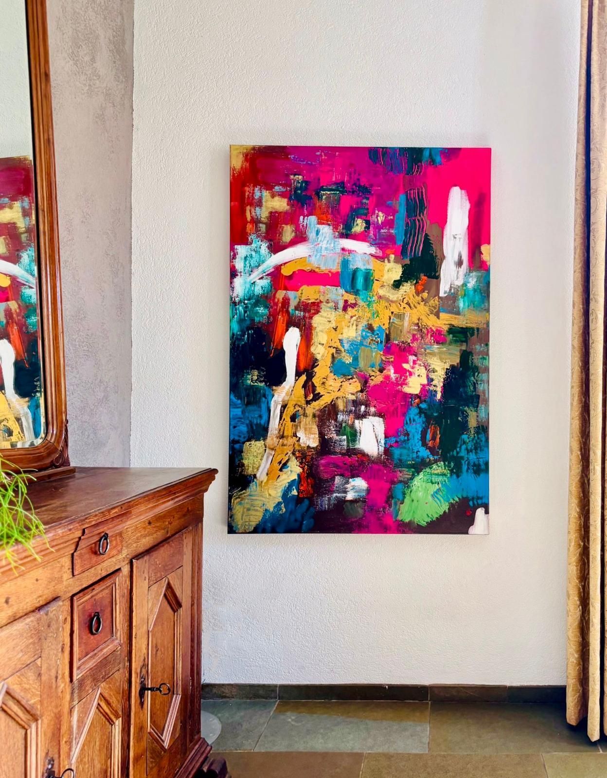 Abstract painting with pink, blue, gold, and white hues hangs on a textured white wall. A wooden cabinet is to the left.