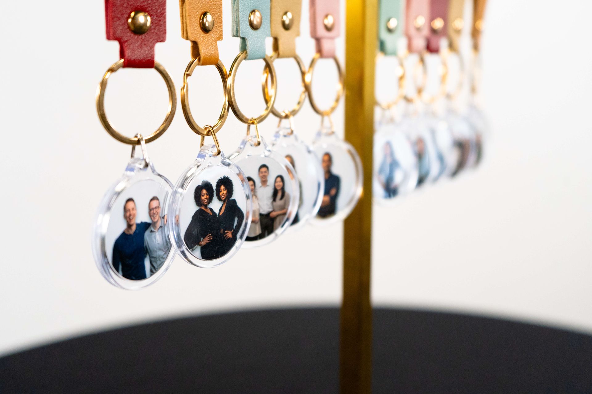 Personalized photo keychains hanging on a gold display stand