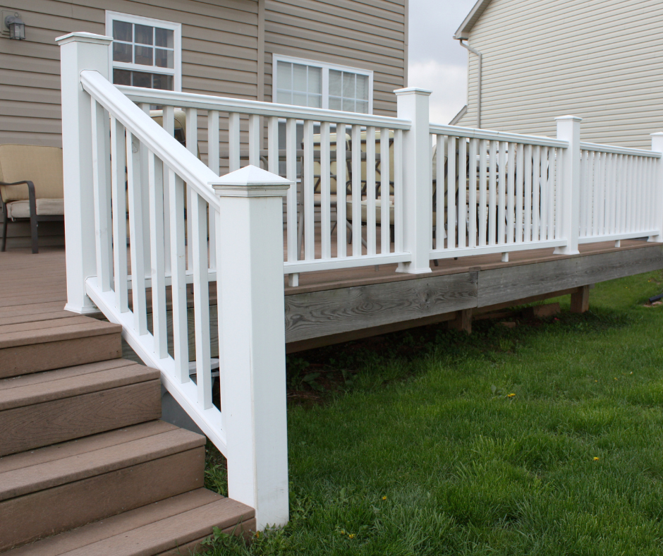 White deck railing and stairs beside a house over a grassy yard
