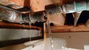 Water is leaking from a pipe in a basement.