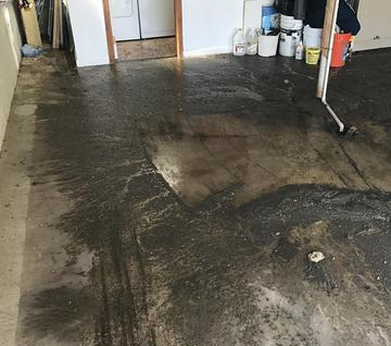 A dirty floor in a room with buckets of paint on it.