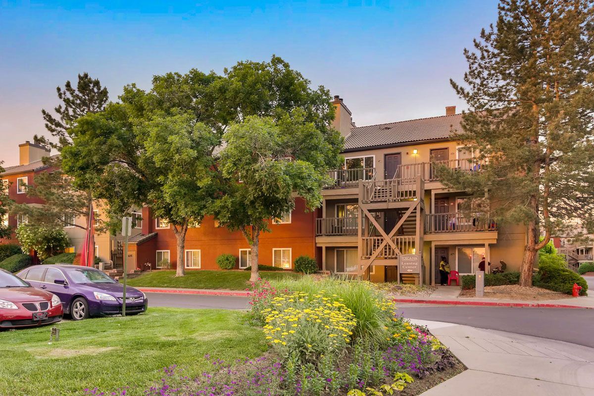 Exterior view of a multi-family building with balconies and landscaped grounds.