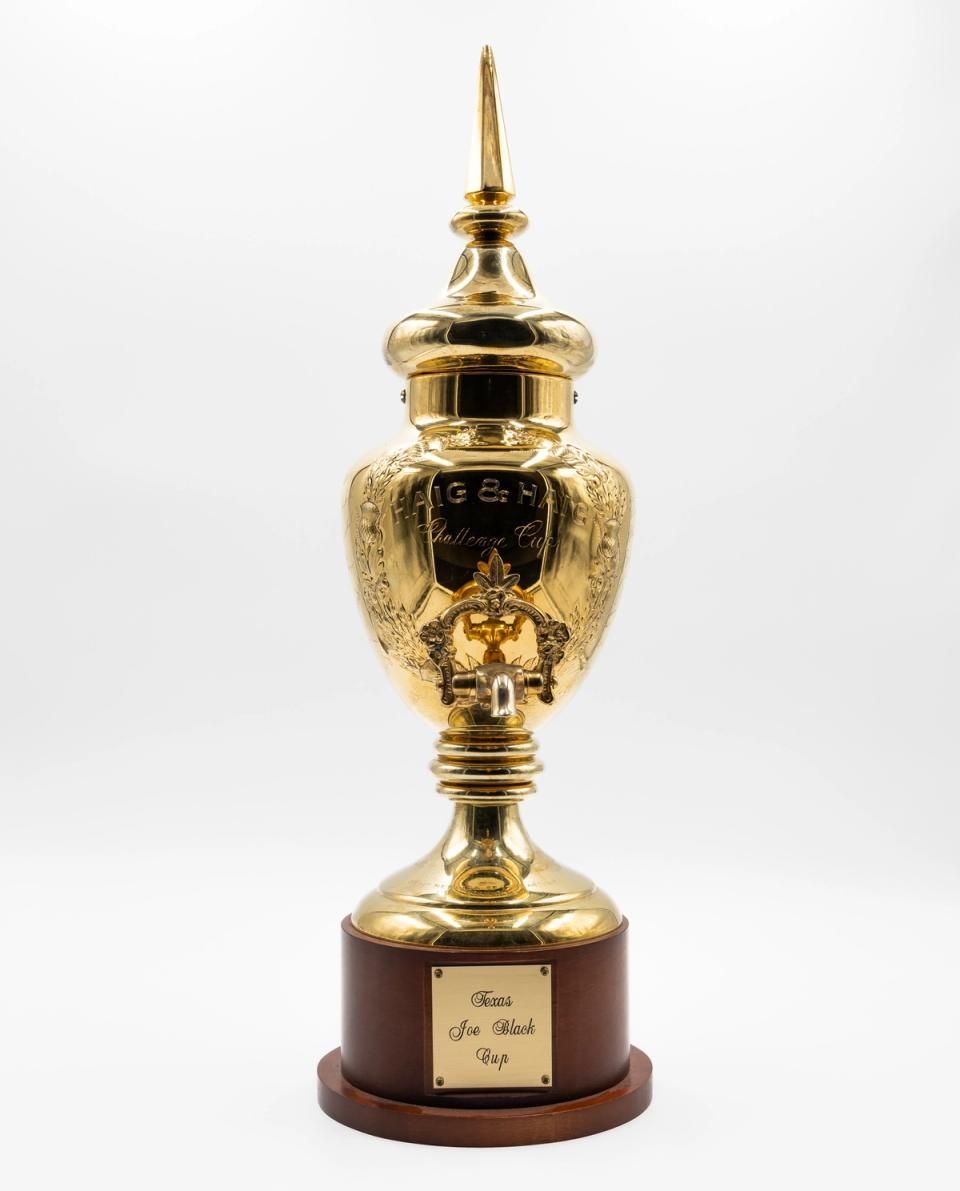 Gold trophy with ornate vase-shaped body on a wooden base against a white background