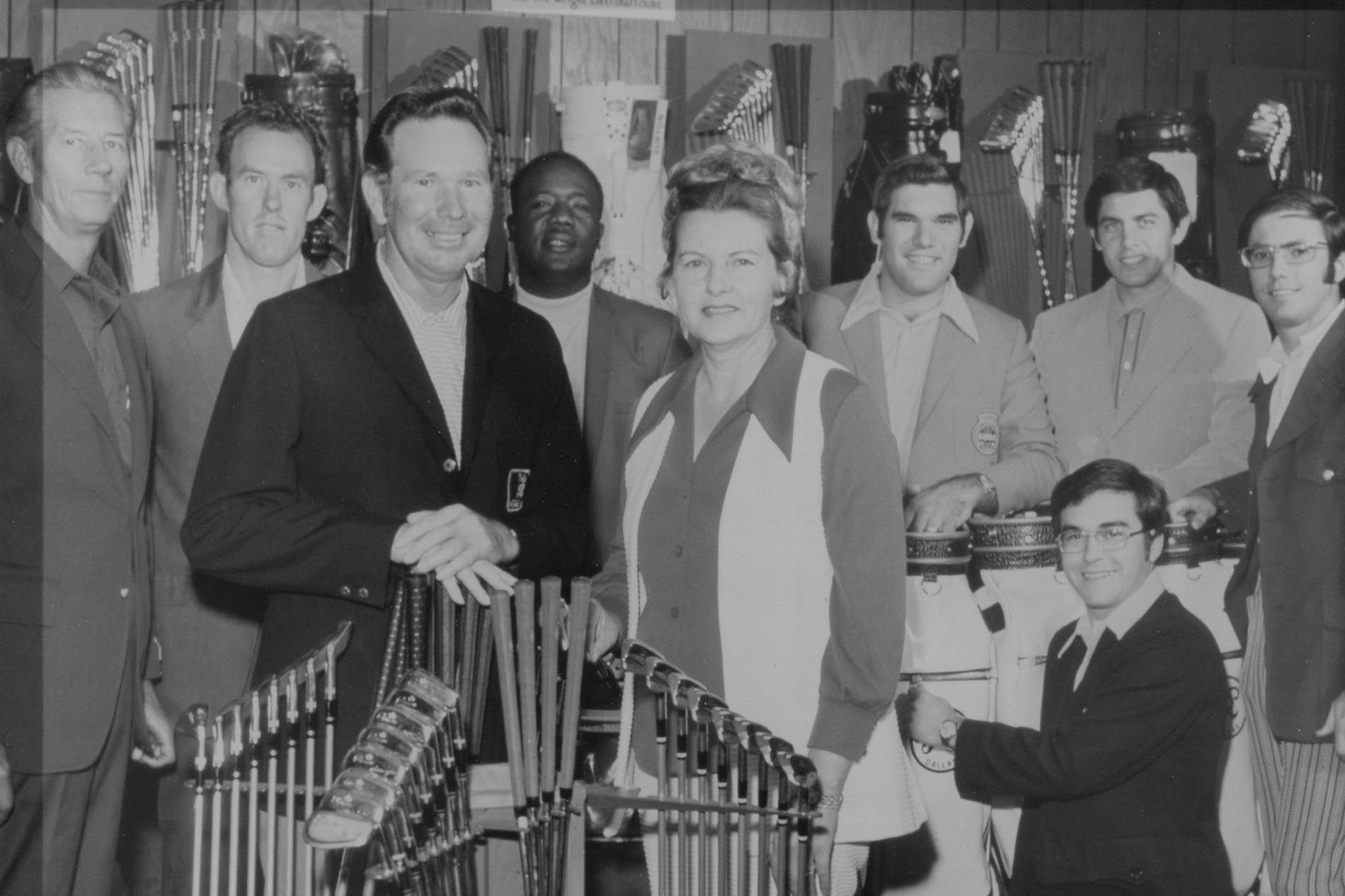 Group of people posing indoors around a microphone stand, with trophies displayed in front.