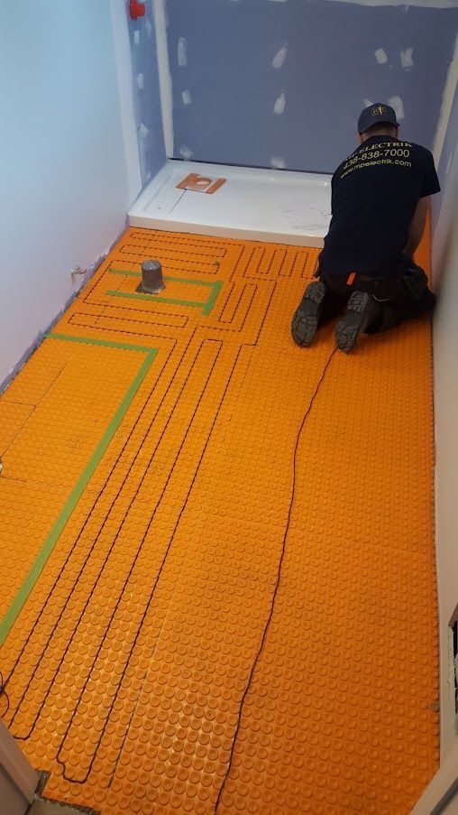A man is kneeling on the floor in a bathroom.