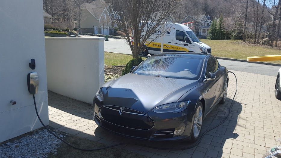 A tesla model s is being charged at a charging station.