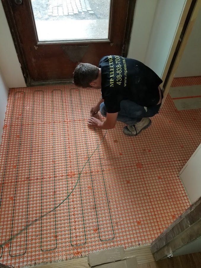 A man is kneeling on a tiled floor in a hallway.