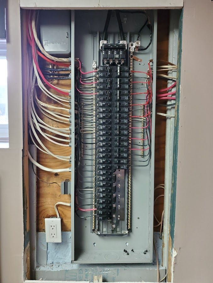 A electrical panel with a lot of wires coming out of it.