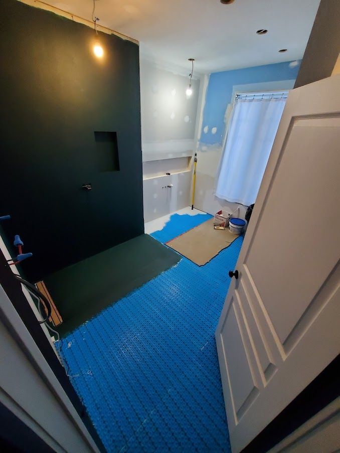 A bathroom under construction with a blue mat on the floor.