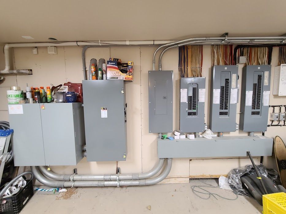 A bunch of electrical panels are hanging on a wall in a garage.