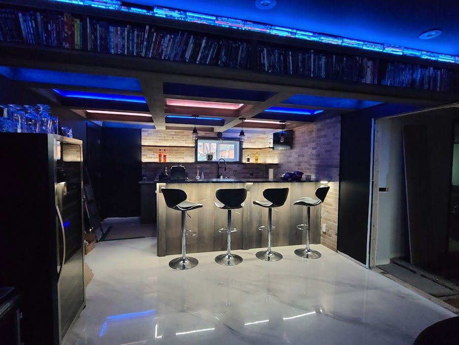 A bar with stools and a refrigerator in a basement.