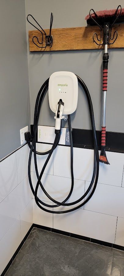 A electric car charger is hanging on a wall in a garage.