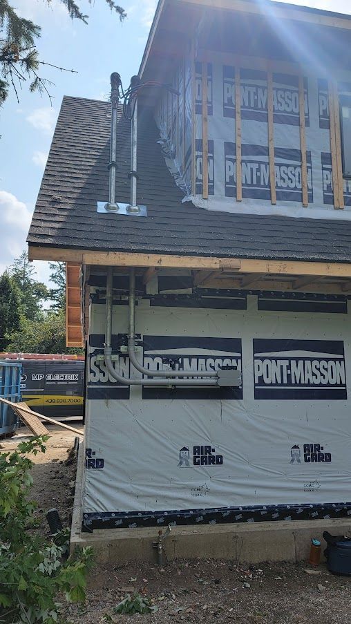 A house is being built with a black roof and a white wall.