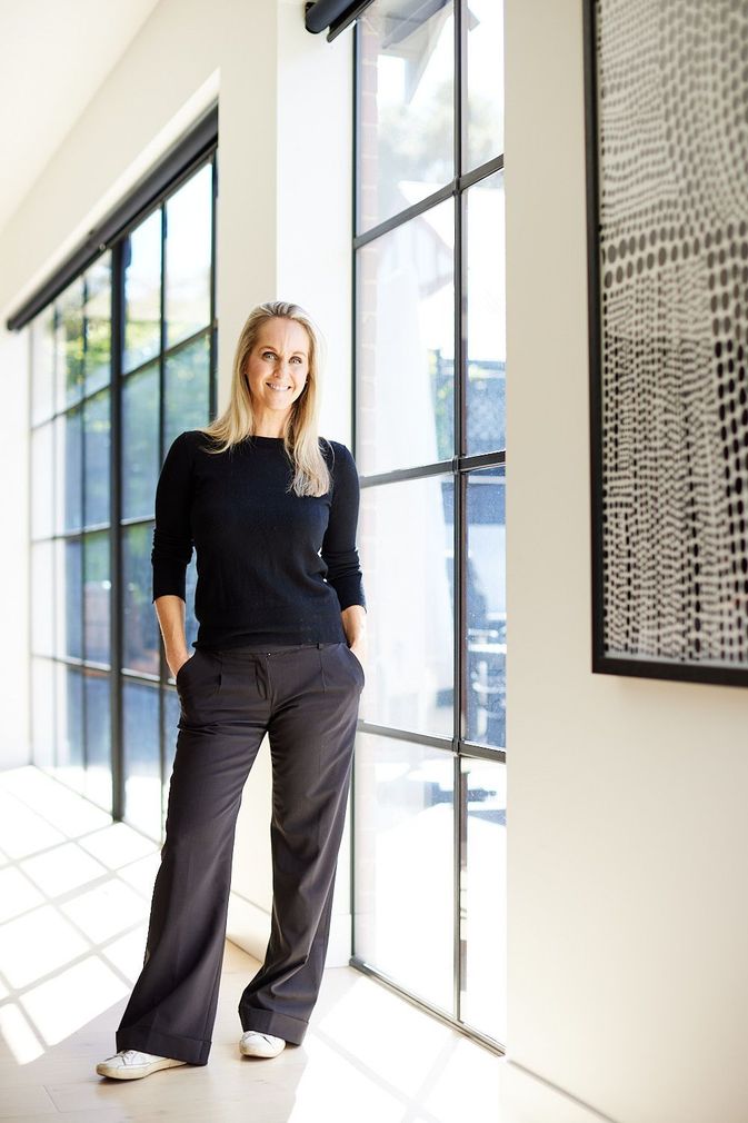 A woman standing in front of a window with her hands in her pockets